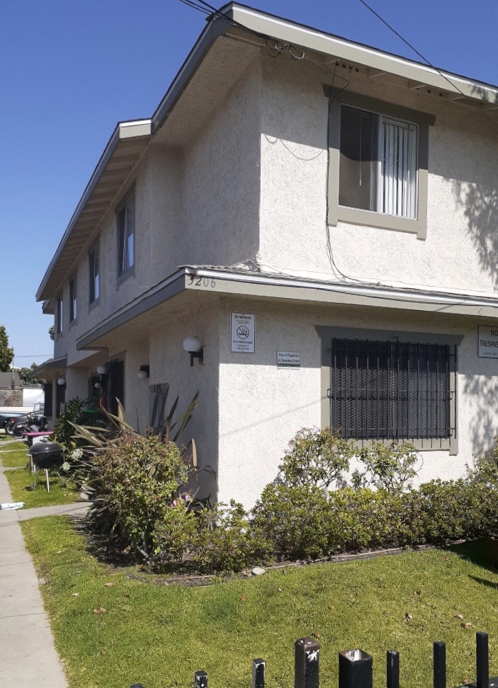 A two-story house with a white facade and a small front yard.